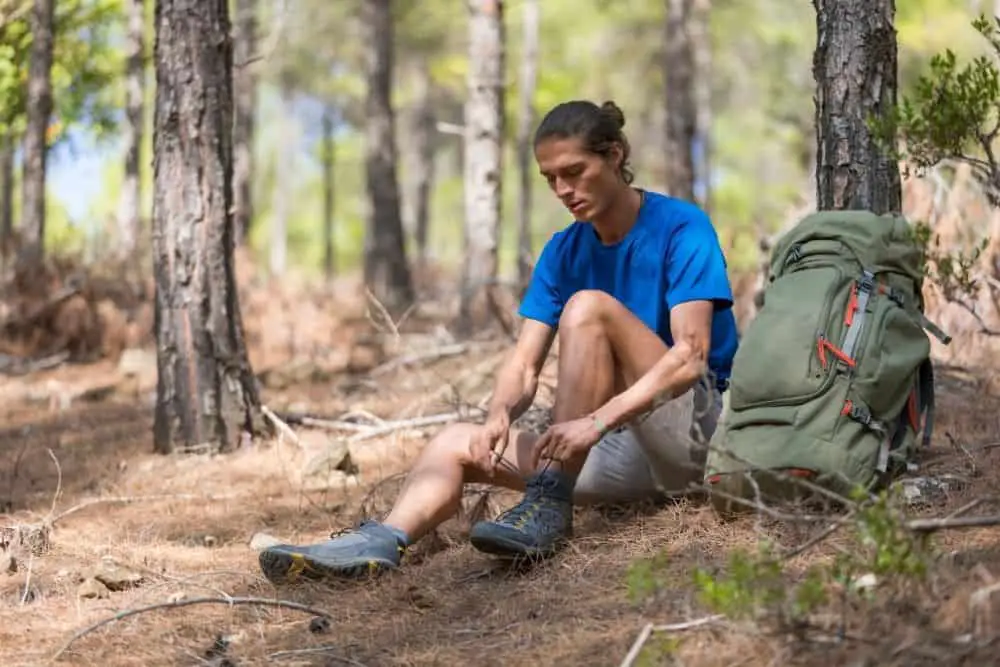 a man tie his hiking boots in forest in garden of the gods