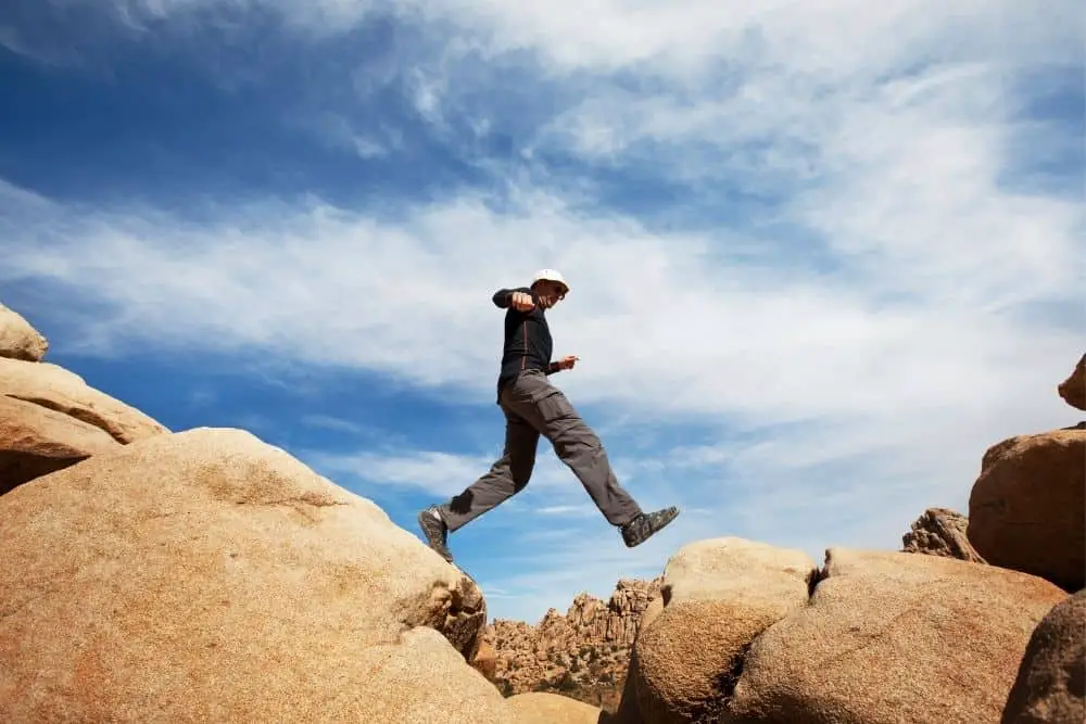 man with hiking boots jumps on rocks in Joshua Tree nation park