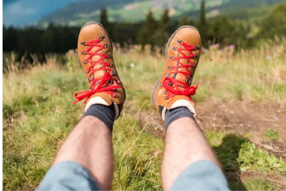 man wear orange hiking boots that have red laces