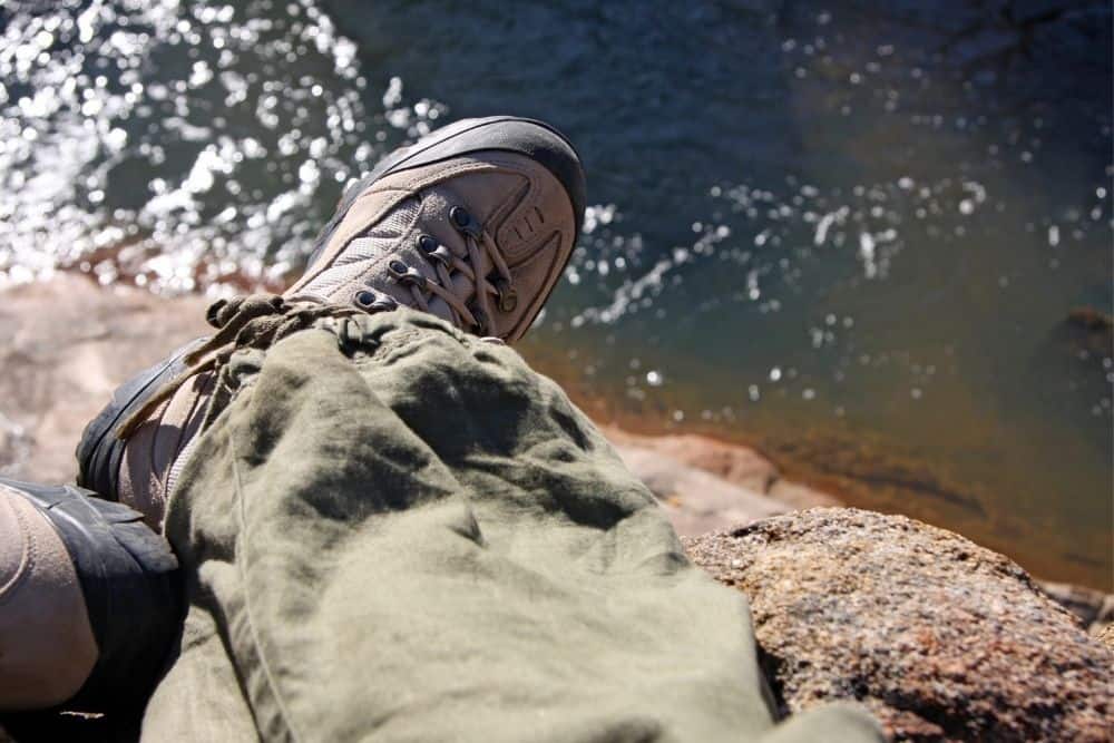 man wearing right size of steel toe hiking boots sitting near a lake