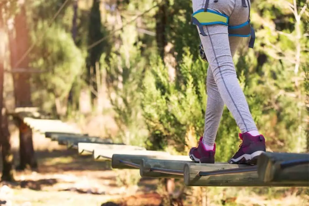 woman walking in pink hiking boots on wooden suspension bridge
