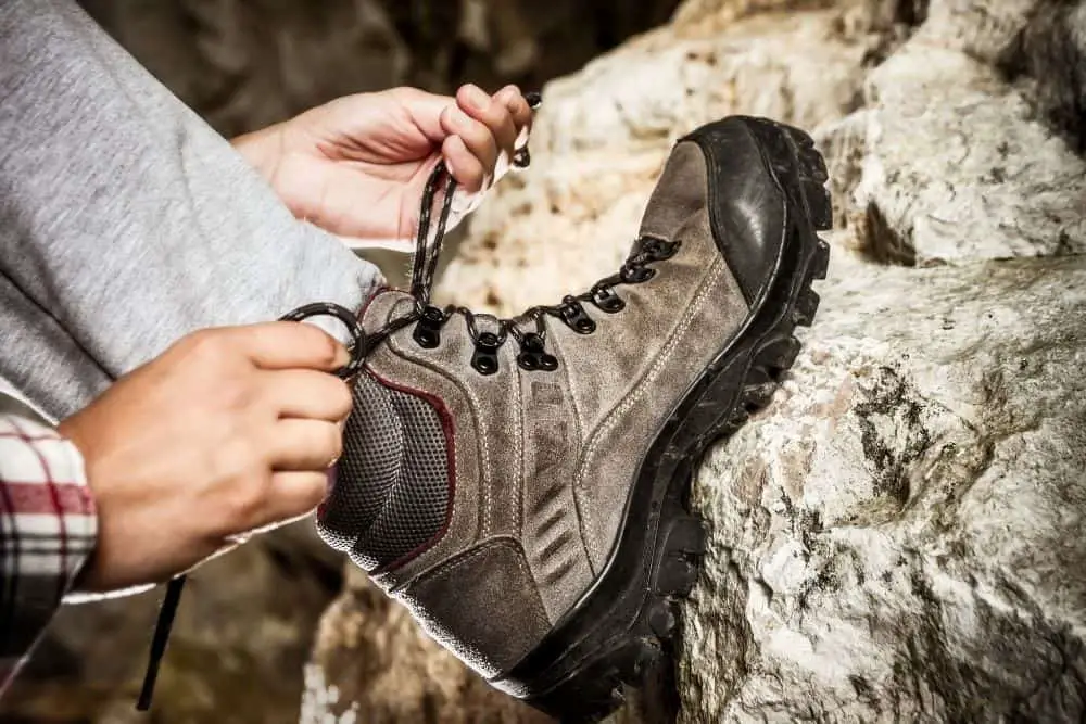 man lacing hiking boots tightly