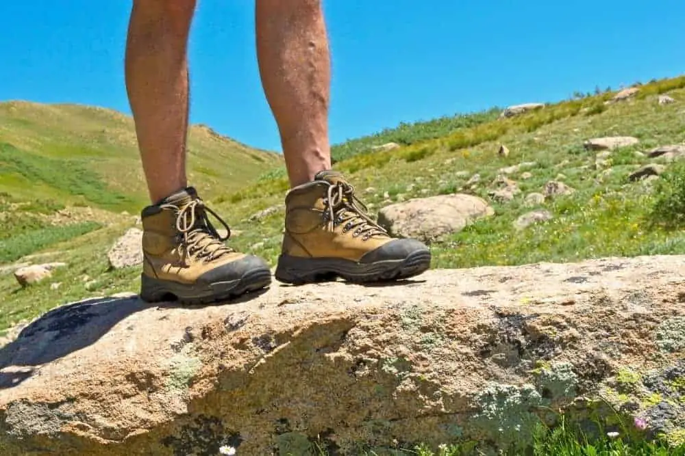 man wearing coyote hiking boot standing on rocky terrain