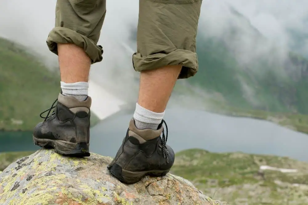 man wearing hiking boots standing on a rock