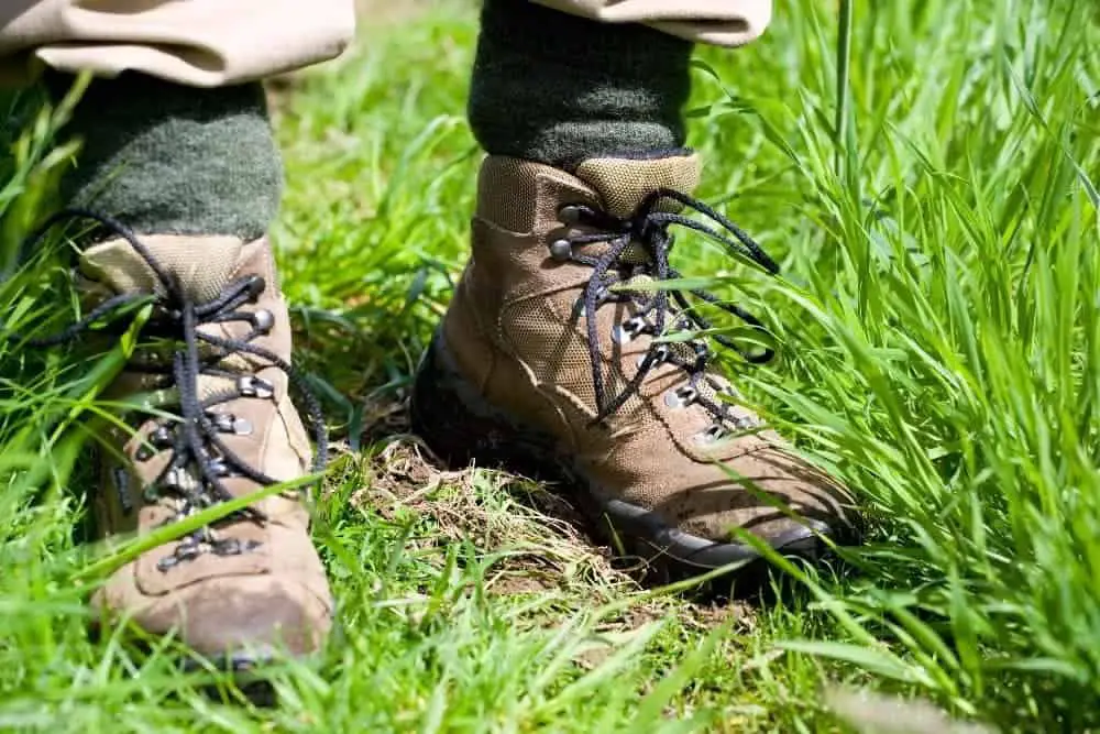 man wearing hiking boots standing on grass