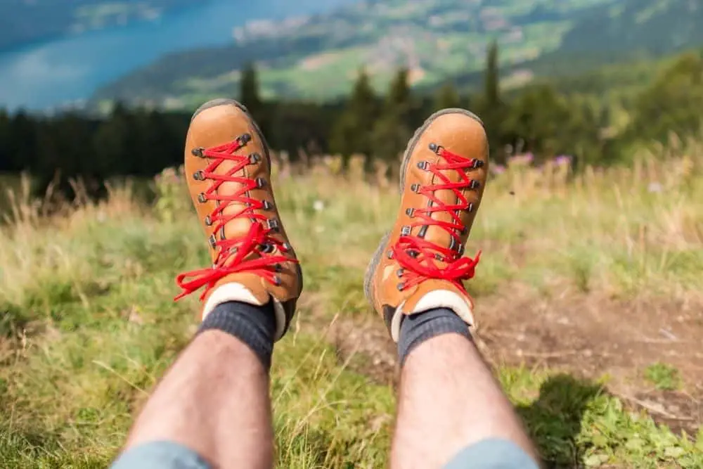 man wearing gray socks, brown hiking boots with red laces