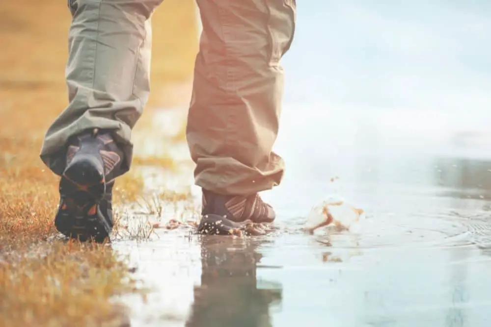 man wearing hiking boots walking in mud