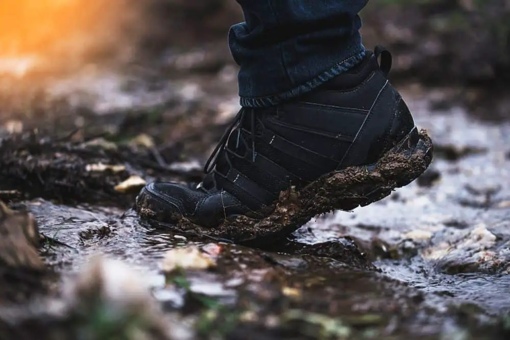 man wearing lightweight hiking boots lifting his heel off mud
