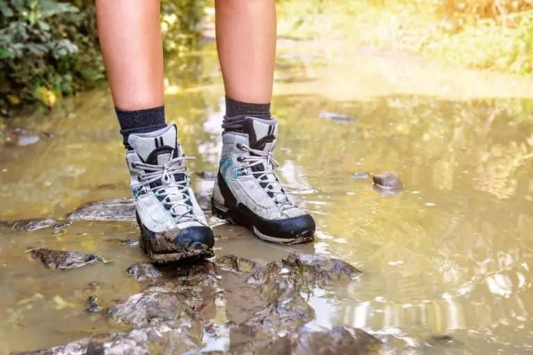 man wears hiking boots in muddy and wet area