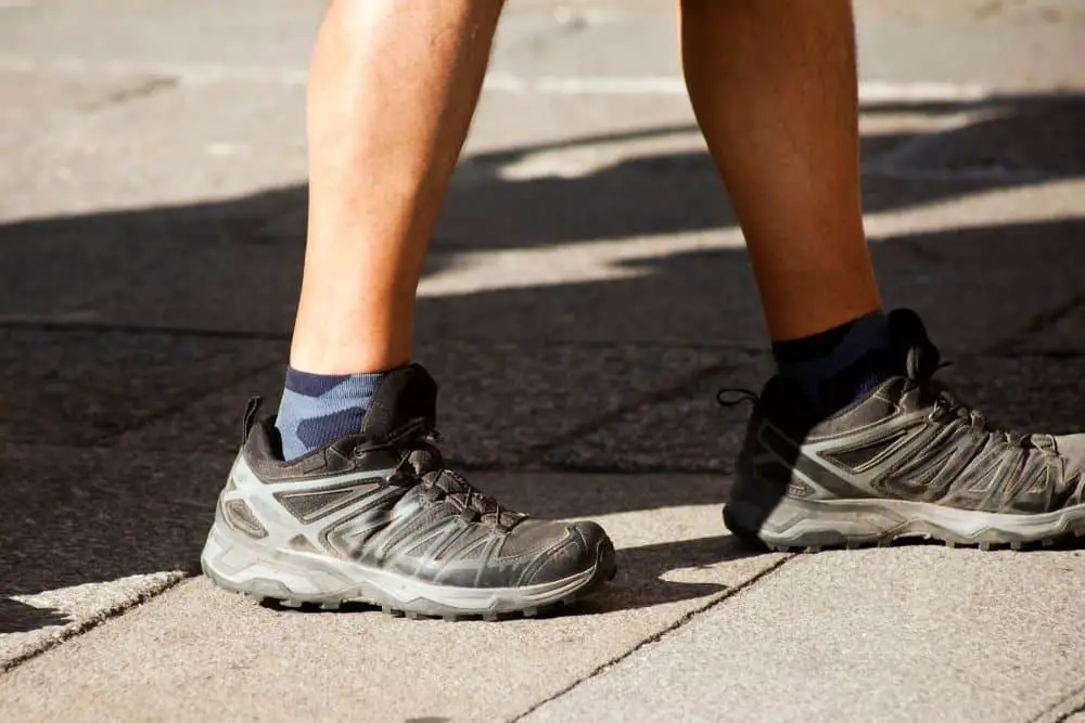 man wears hiking boots with socks walking on road