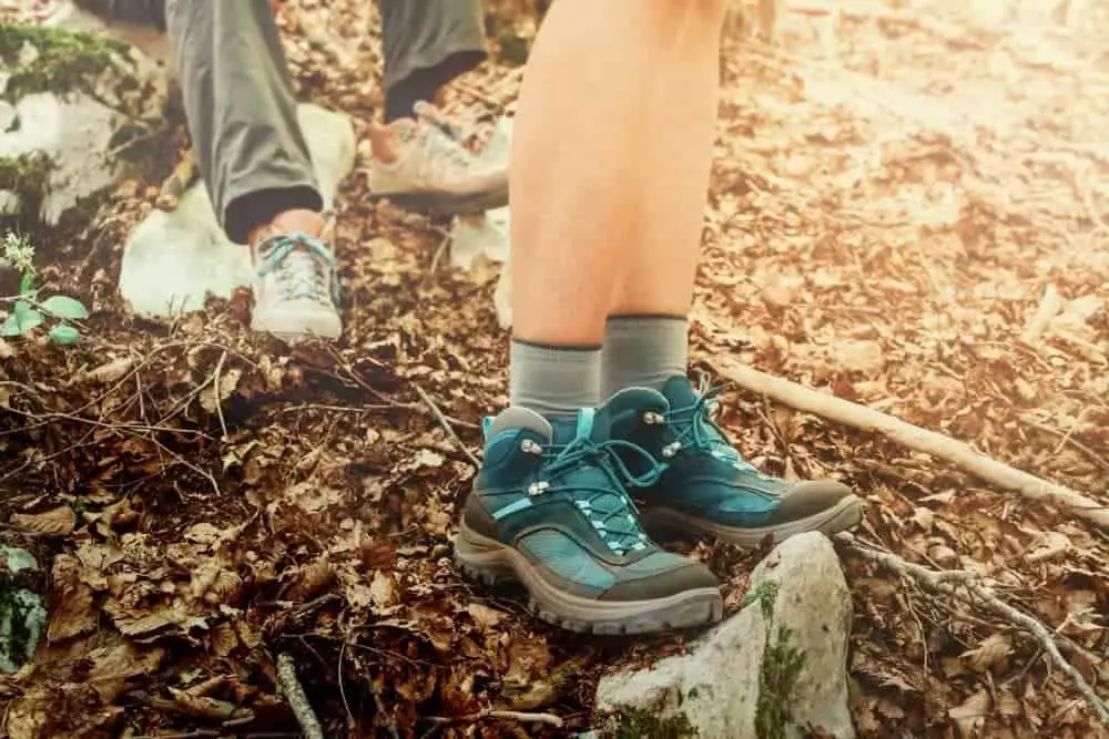 two people wearing broken in hiking boots in forest