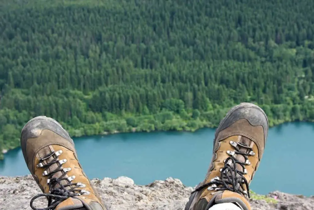 Men wear hiking boots sit on the rocky mountain near the river
