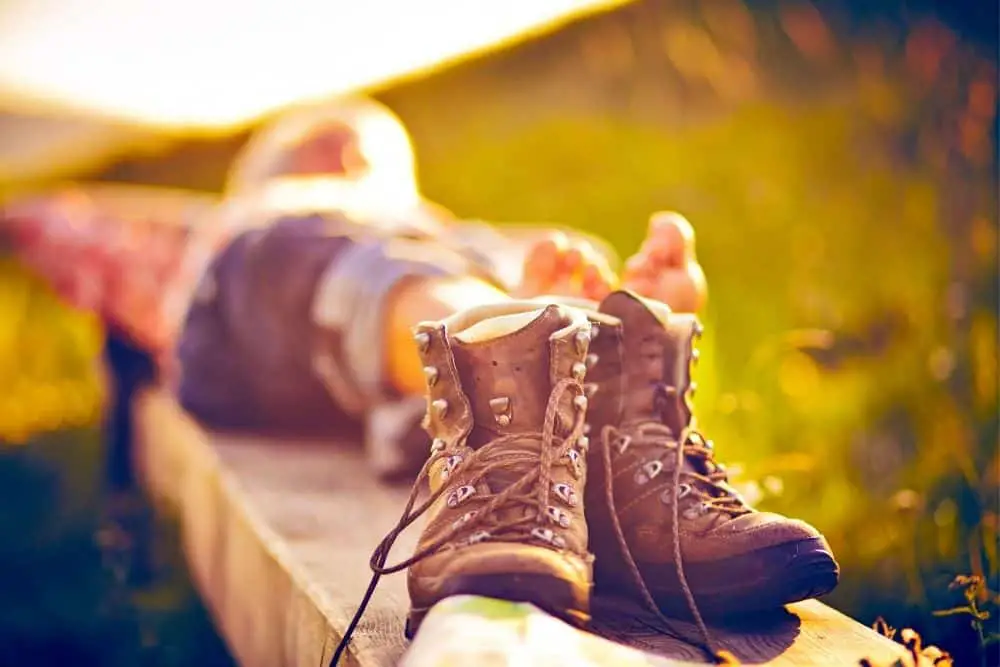 a person lying next to a pair of hiking boots