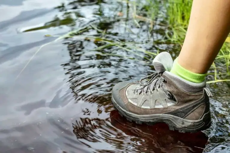 man wearing waterproof hiking boots through a puddle