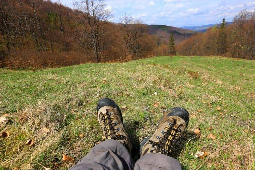 man wears hiking boots sitting on grass