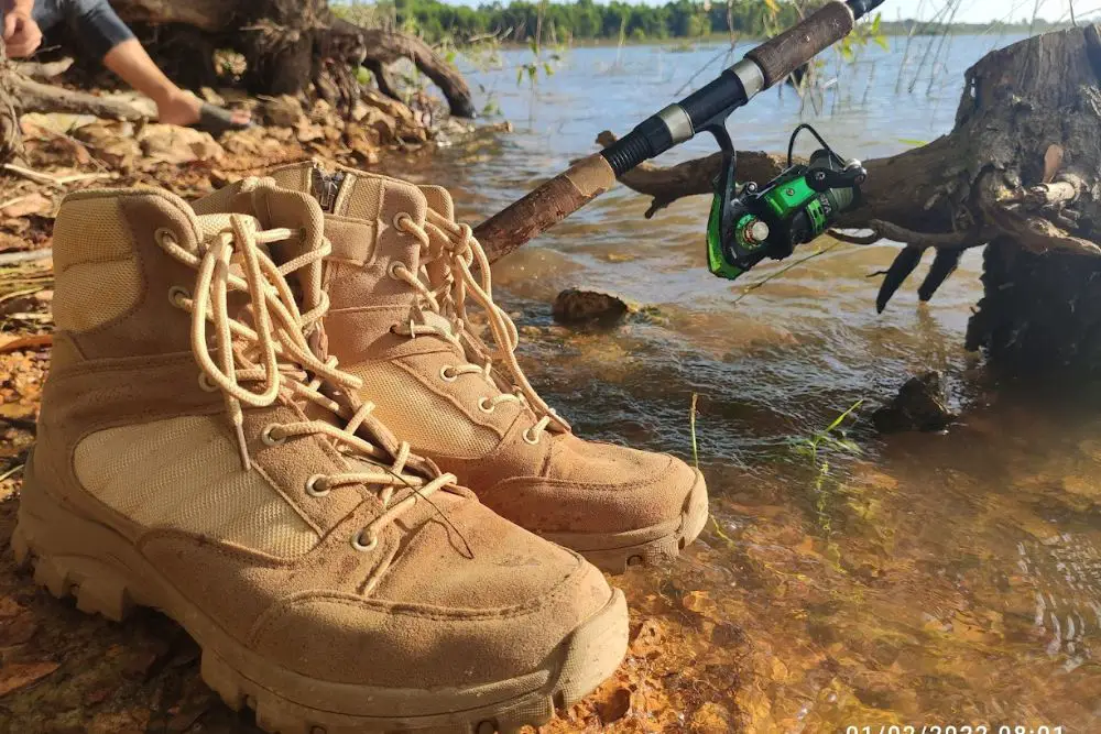 Hiking boots and fishing-rod near the lake