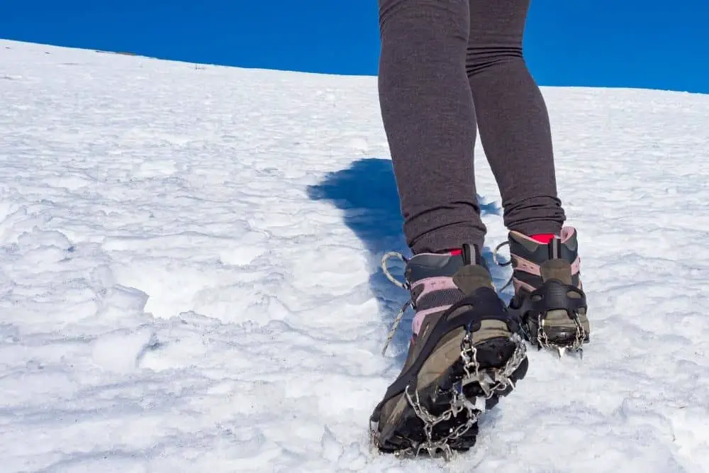 silver Crampons With pink Hiking Boots on snow