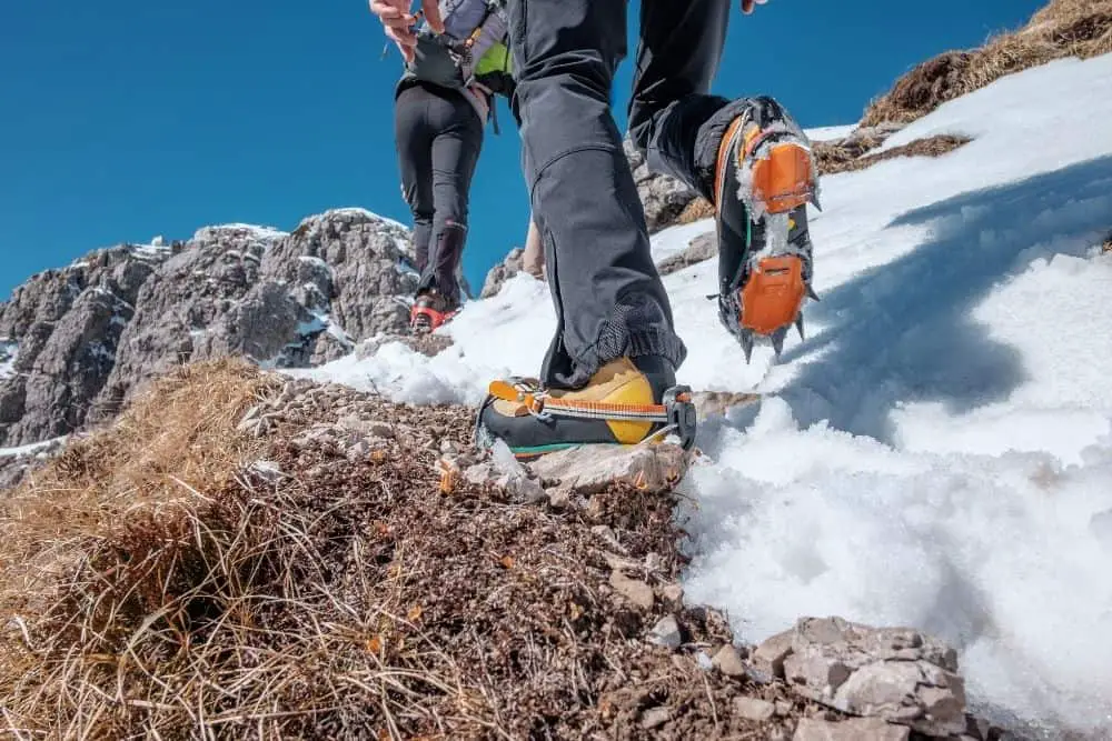 silver Crampons With yellow Hiking Boots on snow