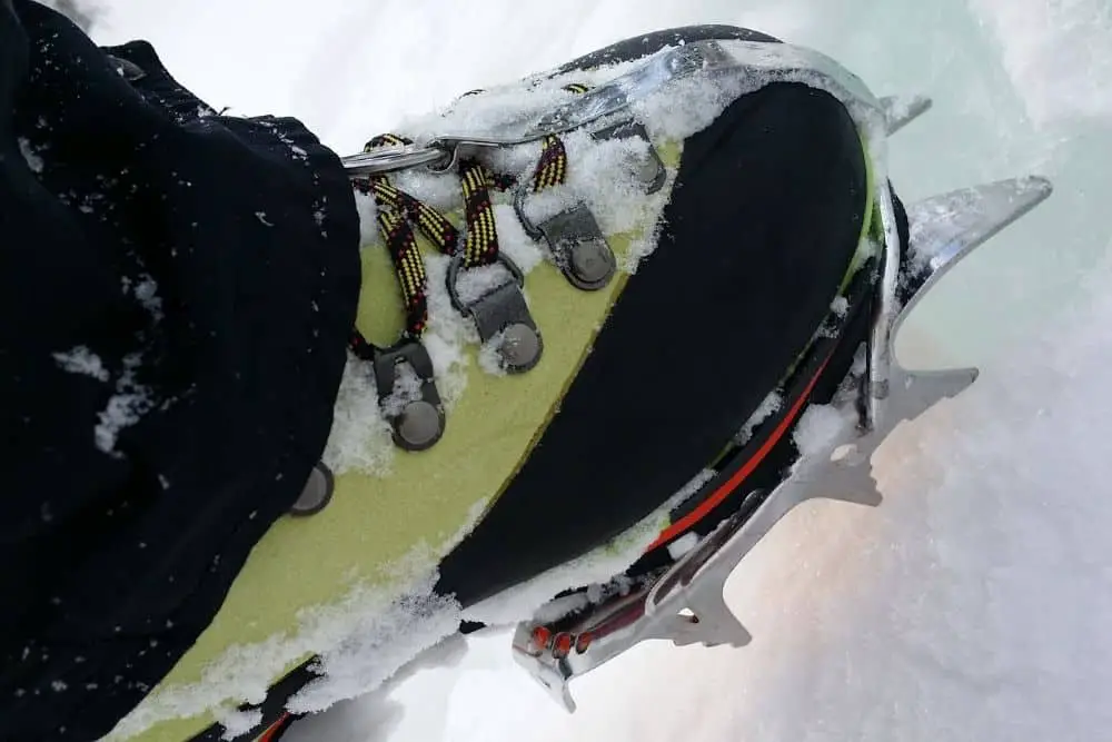 white Crampons With green Hiking Boots in snow