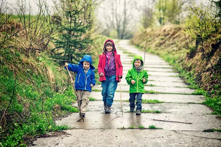 Kids wear hiking boots and are walking in the rain