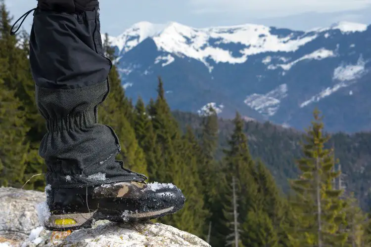 Man wear wet high cut hiking boots in the snow mountain