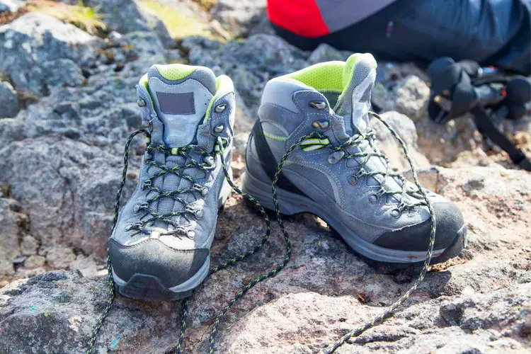 a woman removes hiking boots and breaks on the rock