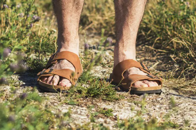 man wears hiking sandals on dry terrain
