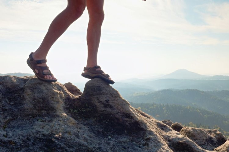 man wears hiking sandals on rocky uneven terrain