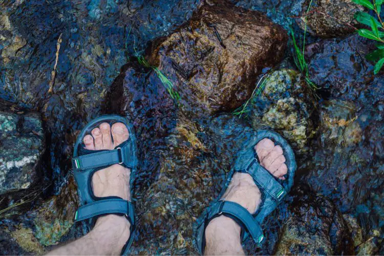 man wears hiking sandals passing through a river