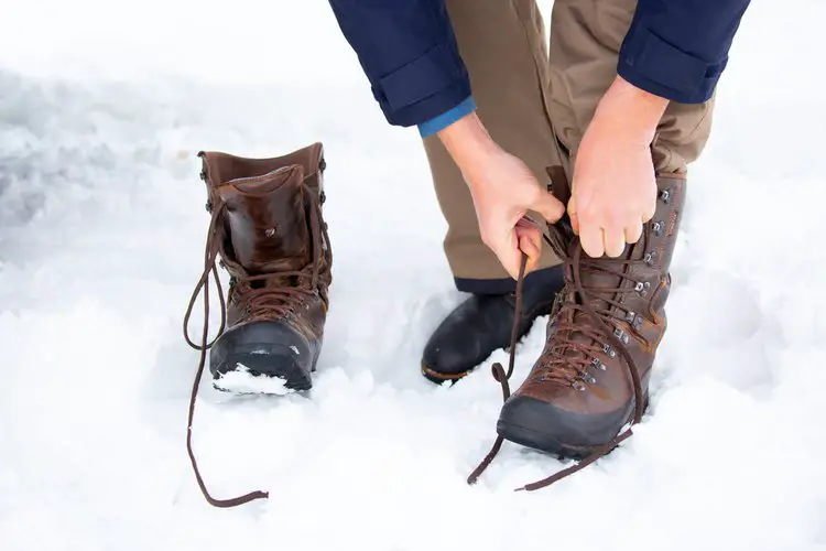 man wears leather hiking boots in the snow
