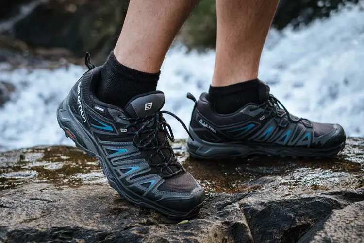 man wears trail running shoes to pass the stream
