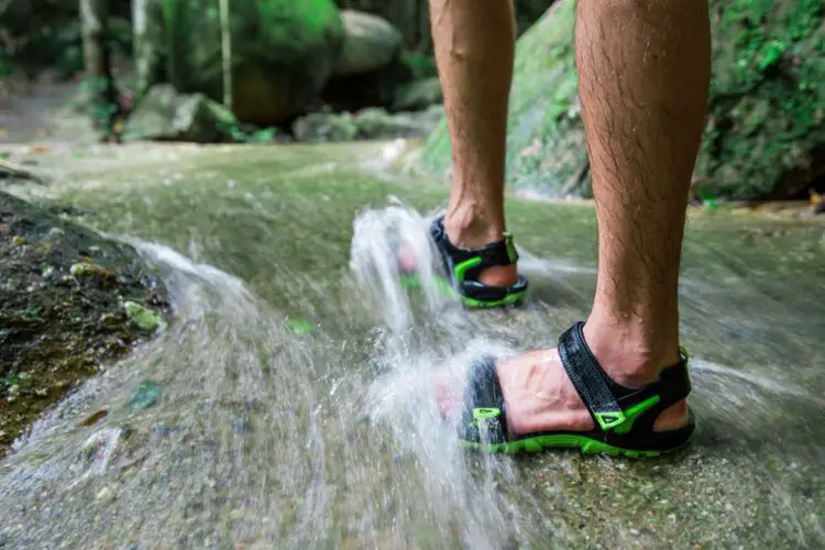 man wears water hiking sandals crossing the stream