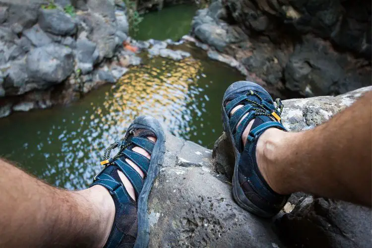 man wears water hiking sandals to cross a stream