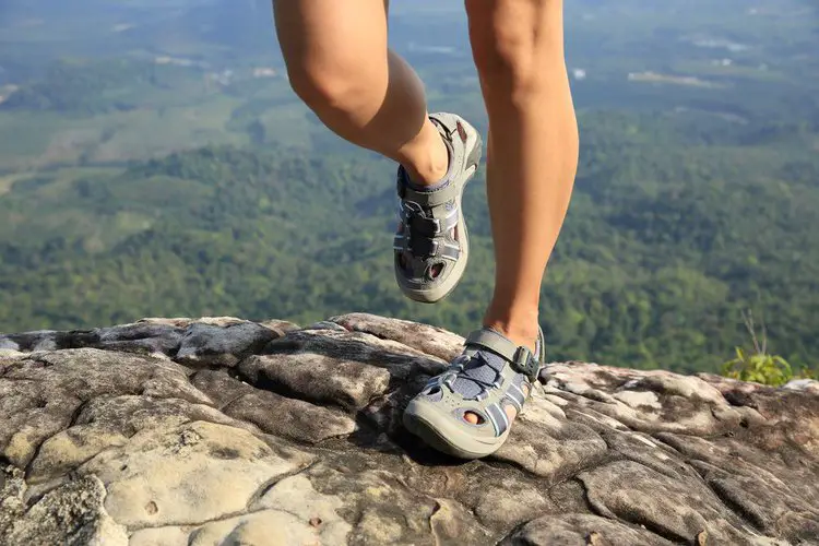 woman wears closed toe hiking sandals walking on the big rock