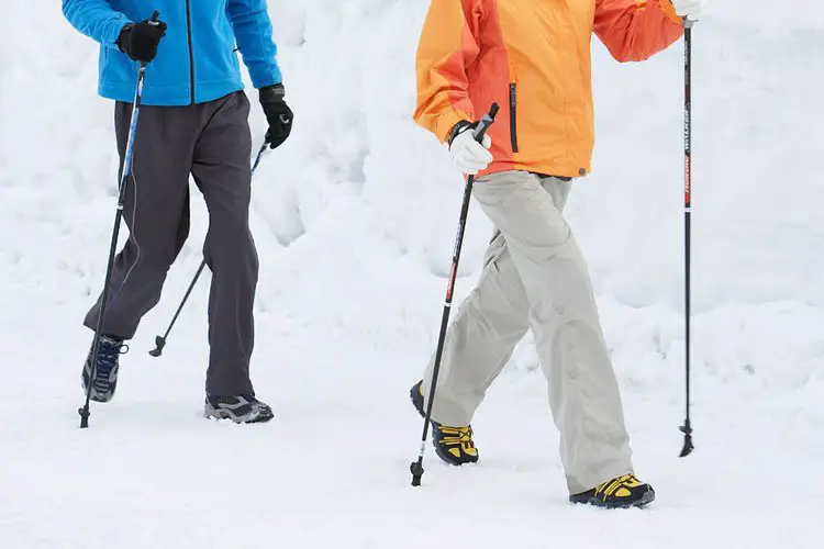 a couple hiking in the snow with hiking poles