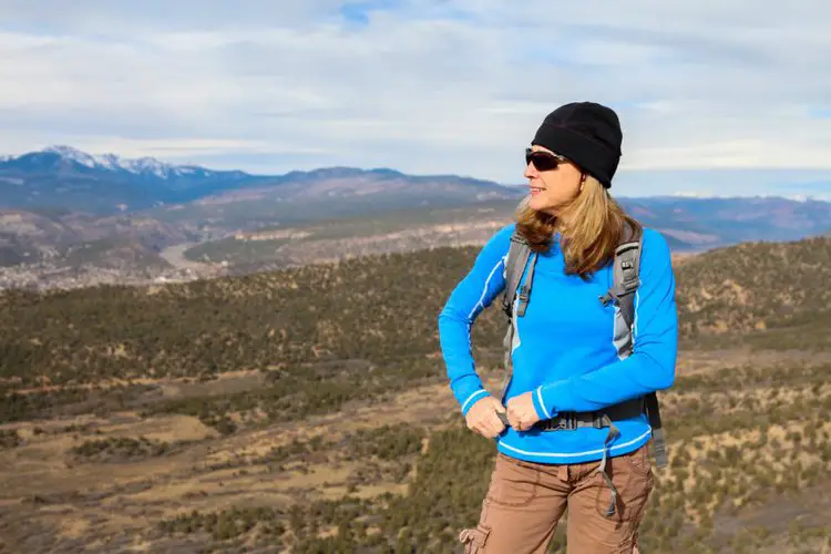 a girl adjusts the hip belt of hiking backpack