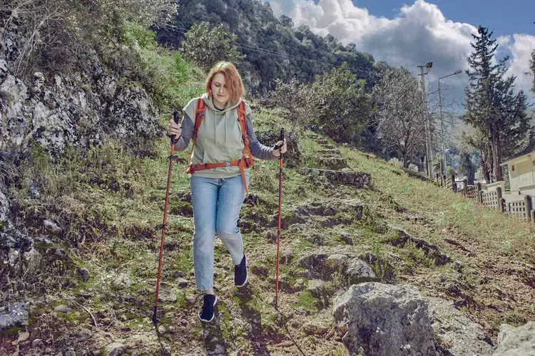 a girl uses hiking poles to keep balanced when go downhill