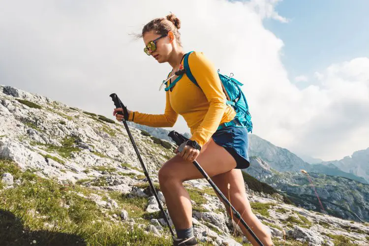 a girl uses hiking straps on the hiking poles to go uphill