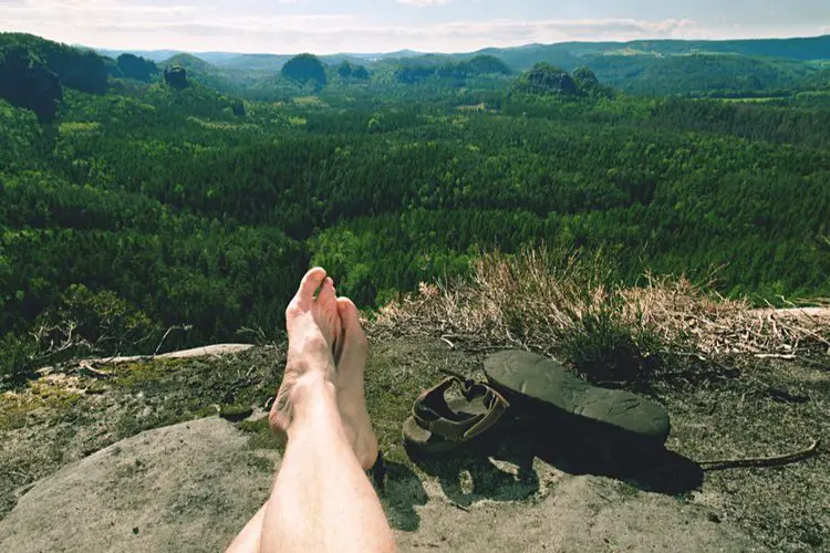 a man takes off hiking sandals and rest while hiking