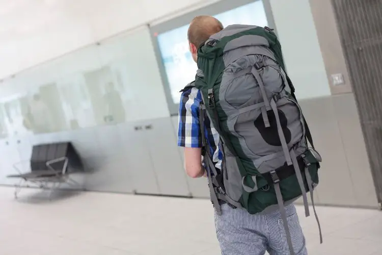 a man wears big hiking backpack at the airport