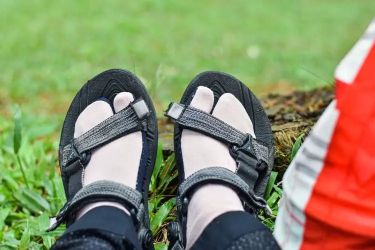 a person wears plain socks with hiking sandals sitting on grass