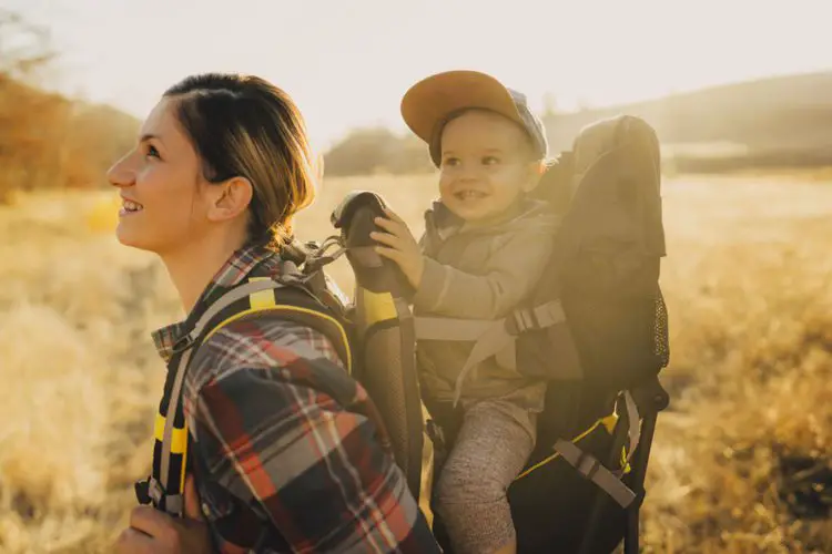 a woman carries a baby in her hiking trip