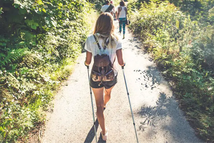 girl uses hiking straps on the hiking poles in hot weather