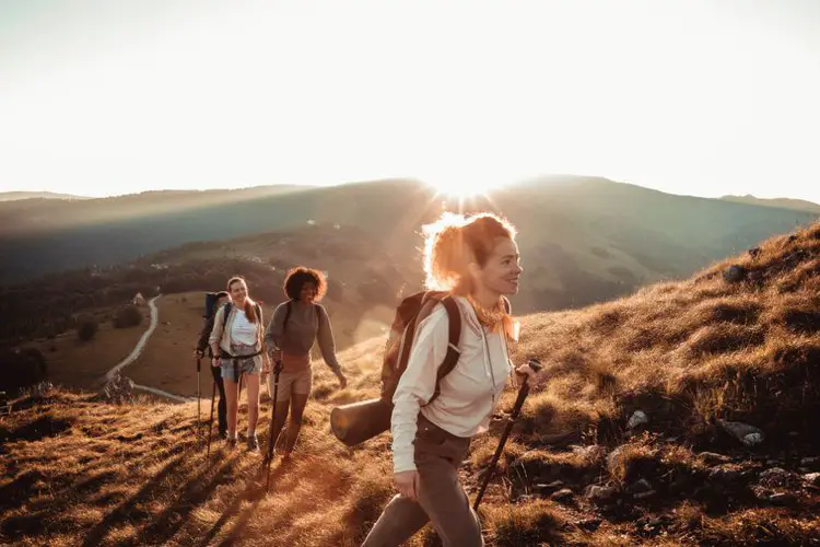 girls with hiking backpacks climbing on a mountain