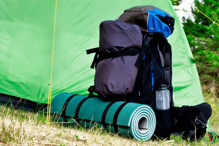 hiking backpack with yoga mat next to a tent