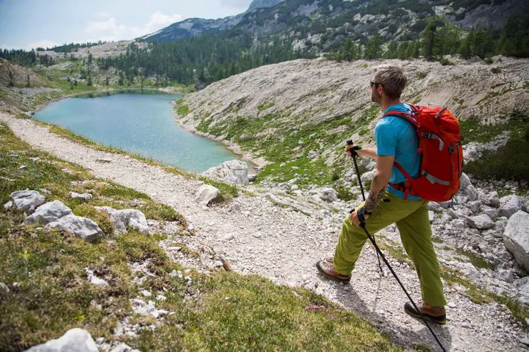 man uses hiking pole straps on rocky terrain