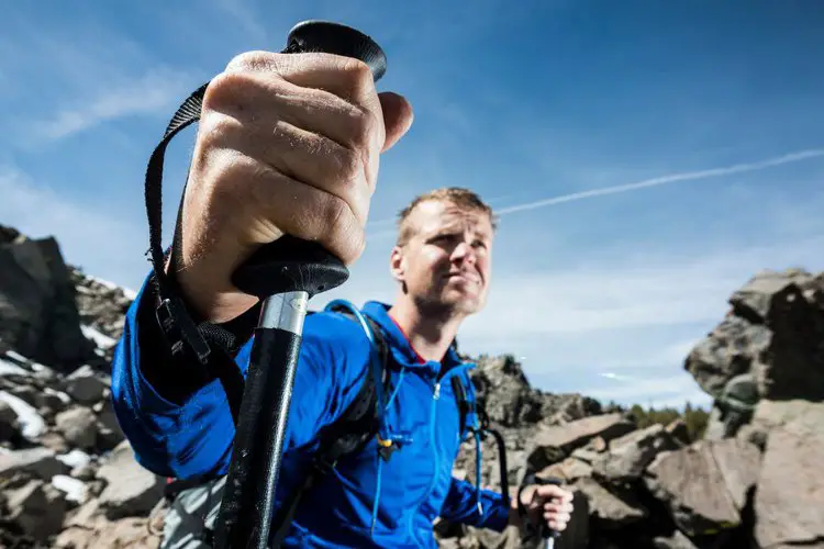 man uses hiking poles for proplusion on rugged terrain