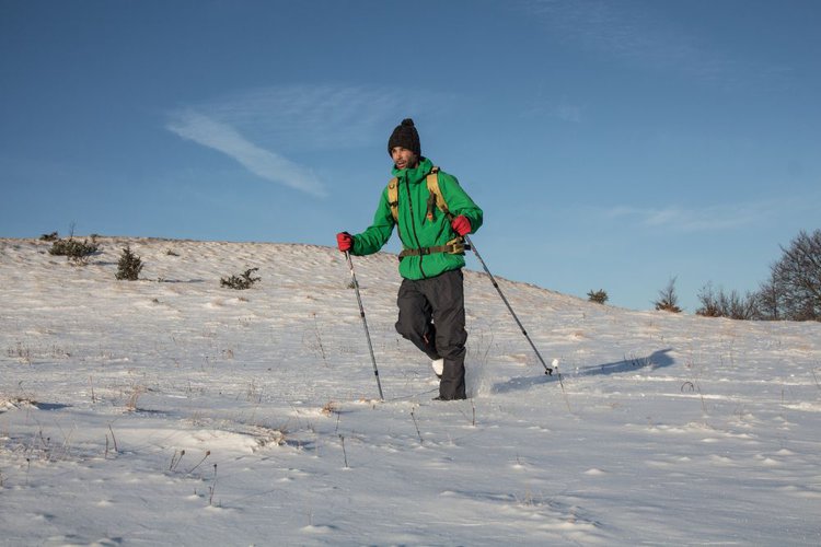 man using hiking poles on thick snowy terrain
