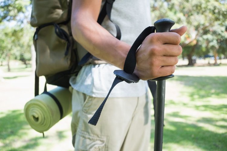 man wears backpack and straps to hold hiking poles