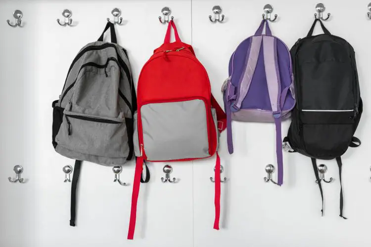 many backpacks are hung on wall with wall hooks